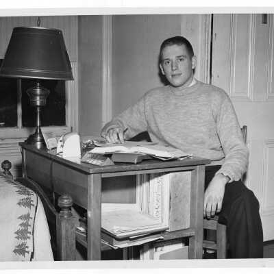 Student resident of Quirk Hall studying at desk in dormitory room.