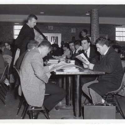 Students sitting at tables in cafeteria.