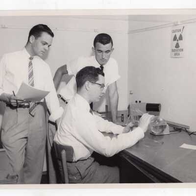 Three graduate chemistry students working in science laboratory, c. 1960.