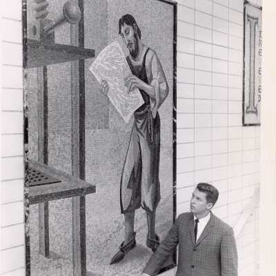 Student standing near mosaic of Gutenberg and the printing press on stairwell wall of Drexel Library.