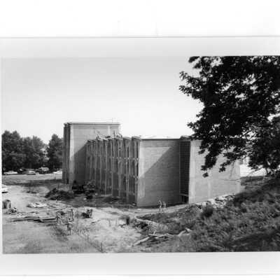 Exterior front view of Bellarmine near end of construction with workmen and view of neighborhood in background.
