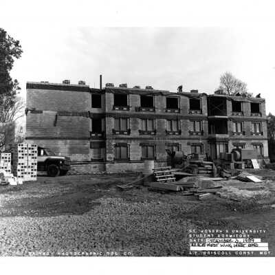 View of McShain Hall construction with workmen and cement mixer.