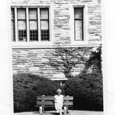 Woman student sitting on bench near Barbelin building in spring?