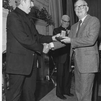 Raymond H. Schmandt(History) receiving 20-year service award from Nicholas S. Rashford, S.J., with Michael Smith, S.J., watching.