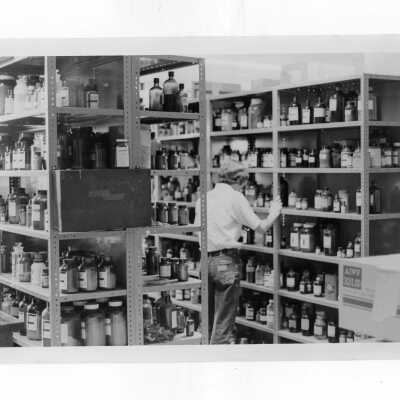 View of supply room in science center with student looking at bottles on metal shelves.