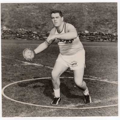 Track team member hurling discus.