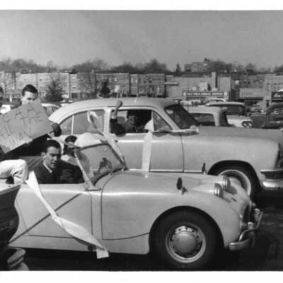 Student booster club car parade/pep rally for basketball with sign saying "NCAA all the way", 1960.