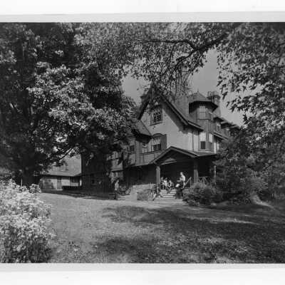 Exterior view of Simpson Hall with students on steps and porch.