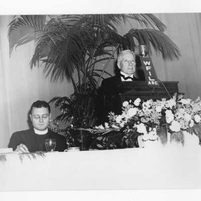 Edward G. Jacklin, S.J., listening to toastmaster, John J. Sullivan (class of 1896) during banquet held in Field House as part of centennial anniversary celebration.