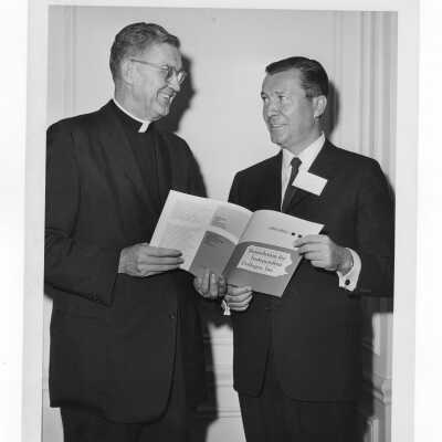 William F. Maloney, S.J., and David Mahoney looking at brochure during Business Ethics Workshop conducted at SJC on November 8 - 9, 1963.