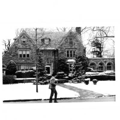 Student walking on Lapsley Lane by Regis Hall with snow on ground.