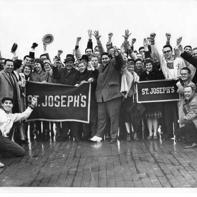 Student booster club cheering and holding Saint Joseph's College banners at pep rally, including Joseph Pascucci and Harry Weinman, 1965.