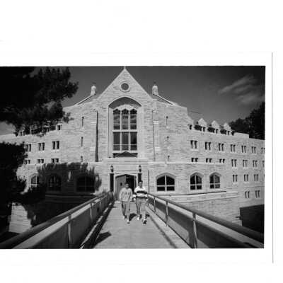 Two students walking on pedestrian bridge with McShain Hall in background.