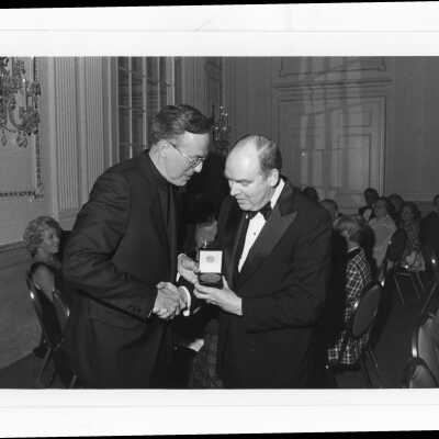 Donald I. MacLean, S.J., presenting alumni award to Henry A. Quinn at alumni awards dinner, c. 1980.