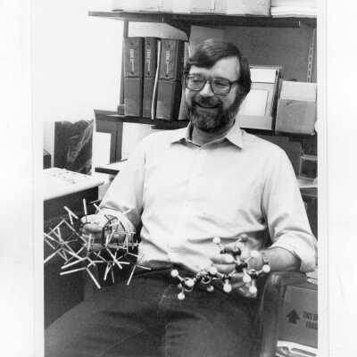 George L. Nelson (Chemistry), working with students in laboratory, and one holding models.