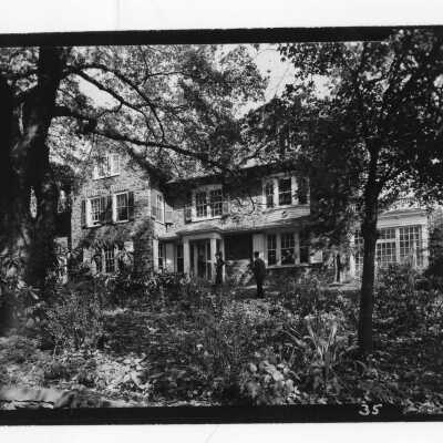 Exterior front view of Greaton Hall with three students standing and talking.