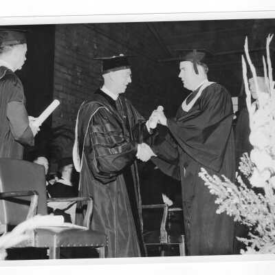J. Joseph Bluett, S.J., handing diploma to graduating student Charles A. Diamond.