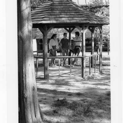 Students talking in gazebo of Gest Estate (now Wolfington Center) in spring. [not original structure; original made with tree limbs]