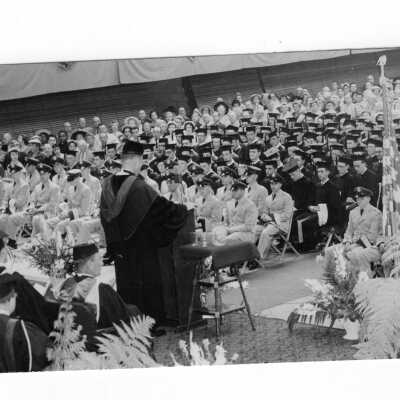 View of 1955 graduation/commencement ceremony in Field House. Two black and white prints.
