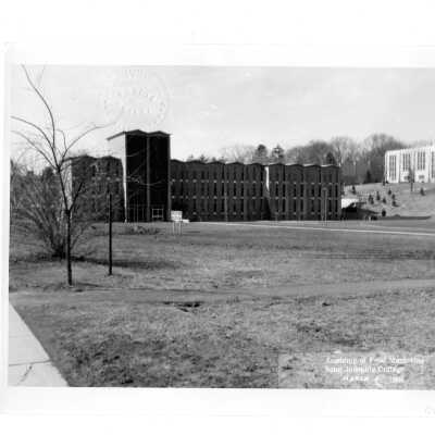 View of lot for Villiger (later Post) Academy of Food Marketing before excavation work began. The photograph is notarized and dated March 4, 1964, and Bellarmine and Drexel Library are in background.