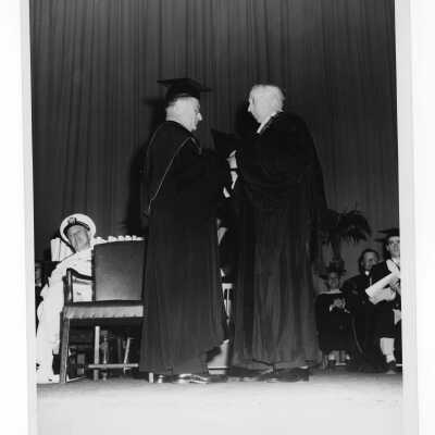 Edward G. Jacklin, S.J., conferring honorary degree to Bernard C. Duffy? during graduation/commencement ceremony, possibly in 1955. Two black and white prints.