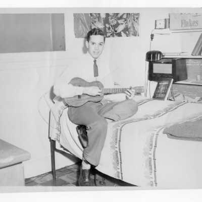 Student from Barry Hall playing a guitar in dormitory room.
