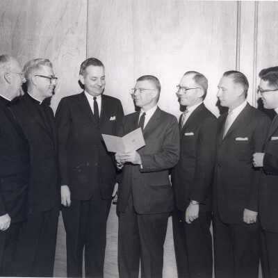Dr. Hilferty, president of medical alumni, showing Shaffrey award program to Mark Bauer, S.J. (recipient), J. Joseph Bluett, S.J., and others1961.