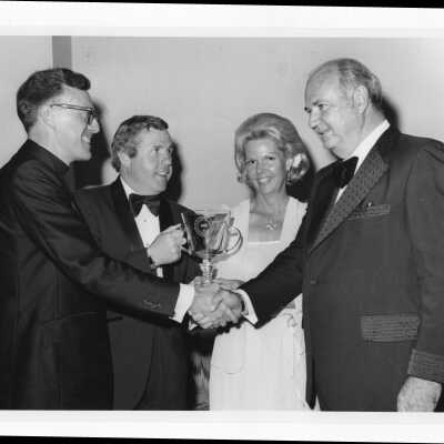 Donald I. MacLean, S.J. presenting 1981 Shield of Loyola Award to Robert Gillin with Richard V. Smith and Mrs Robert Gillin looking on, April 1981.
