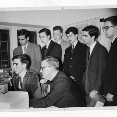 Students in Radio Club (Station WSJR?) with William F. Maloney, S.J. at equipment table.