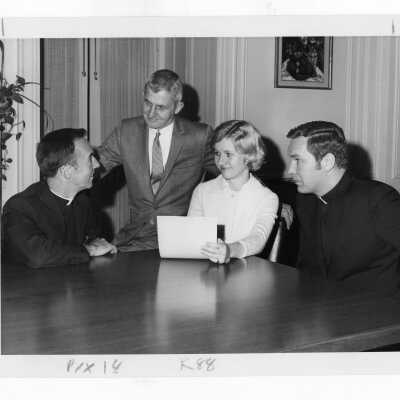 Terrence Toland, S.J., James Moore, S.J., John Adams, Maureen sitting at table discussing coeducation.