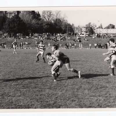 Men's rugby game on Finnesey Field with parking lot and City Avenue in background.