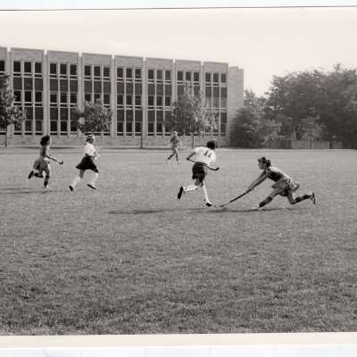 Women's field hockey match on Finnesey Field with Post Hall (formerly Villiger) in background.