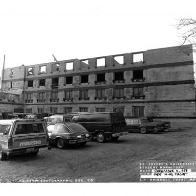 View of McShain Hall construction with workers' cars parked in front.