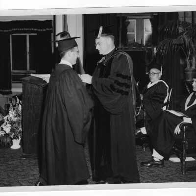 Tropaia exercises during 1955 graduation/commencement with Edward G. Jacklin, S.J. and student, Dominic Roberi?