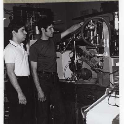 Two chemistry students in science laboratory working with dielectric absorption apparatus, c. 1970.