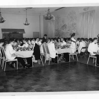 Students in formal dress eating dinner at dinner dance.