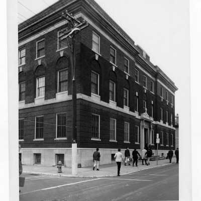 Students wearing coat and tie walking in front of Gesu Convent in Philadelphia with nun standing at doorway.