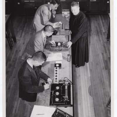 Physics professor, John S. O' Conor, S.J., working with three students in laboratory, November 1958.