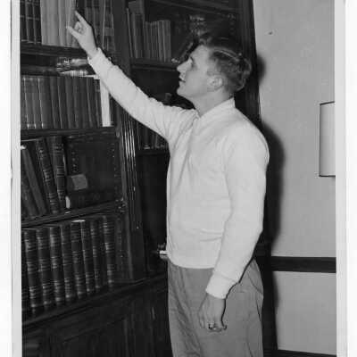 Student resident of Quirk Hall standing in front of bookshelf.