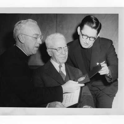 Dr. J. Parsons Schaeffer showing Shaffrey award medal to J. Joseph Bluett, S.J., and Father MacEntee, 1959.