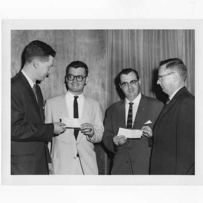 Tom Carmody and other alumni association officers holding check from fundraising event, June 12, 1961.
