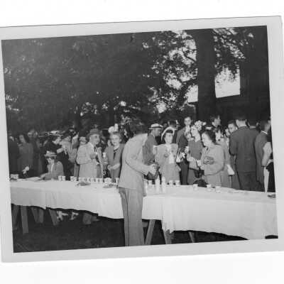 Guests attending 1948 graduation/commencement ceremony eating and drinking at outdoor reception after ceremony.