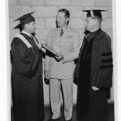 Tropaia exercises during 1955 graduation/commencement with Alumni President, W. Ariano, Edward G. Jacklin, S.J., and military officer after ceremony.