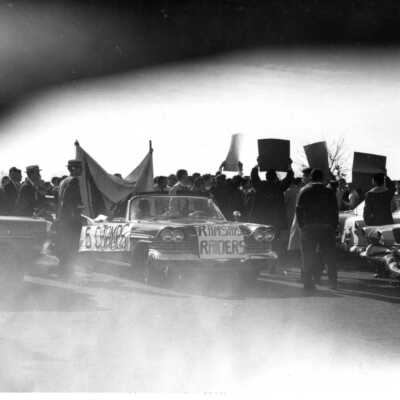 Student booster club pep rally/car parade, with signs saying "Ramsay's Raiders" and "5 Champs."