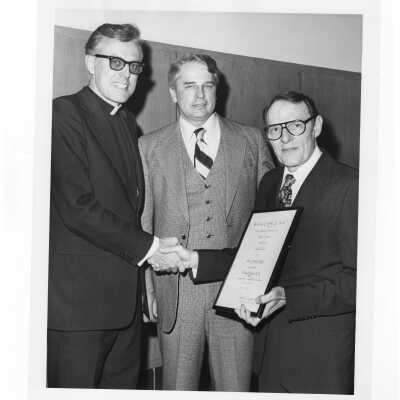 Donald I. MacLean, S.J., congratulating Shaffrey award recipient, Dr. William F. Kellow, with Gerard Kaiser watching, April 23, 1978.