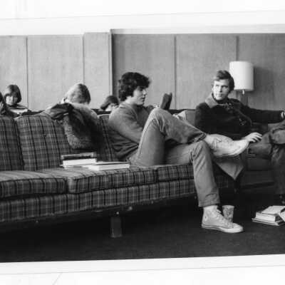 Several students studying in lounge area sitting on sofas and chairs.