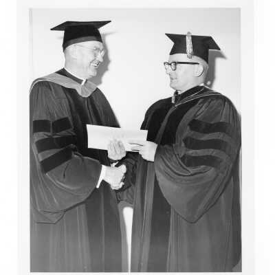 William F. Maloney, S.J., congratulating Dr. George Beichl, Chemistry Professor and recipient of Lindback Award, during October 1963 graduation/commencement.