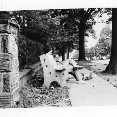 Two students sitting and talking on bench along City Avenue.