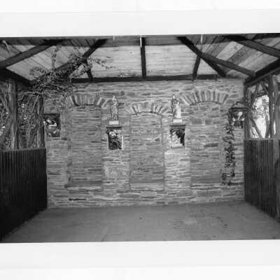 Interior of old gazebo with stone wall and ceramic sculpture of Boland Hall.
