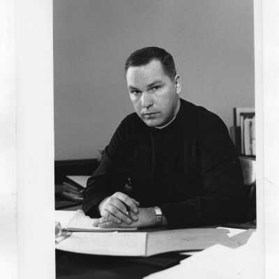 James W. Moore, S.J.,as Assistant Dean of Admissions ?, sitting at desk.